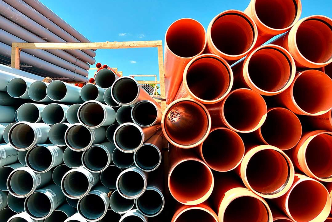 Piles of gray and orange PVC pipes for water piping systems