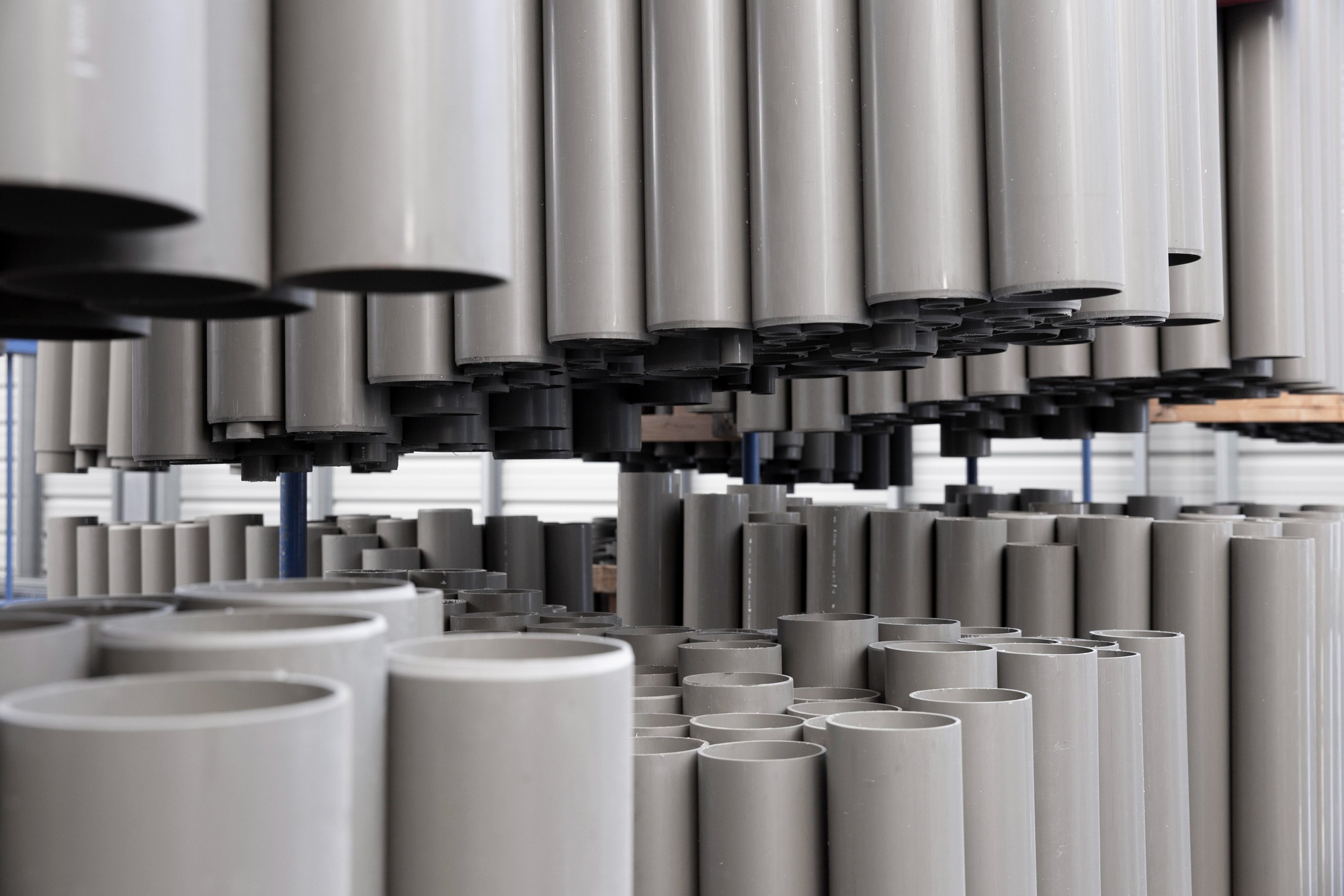 Stacks of grey plastic pipes in a factory